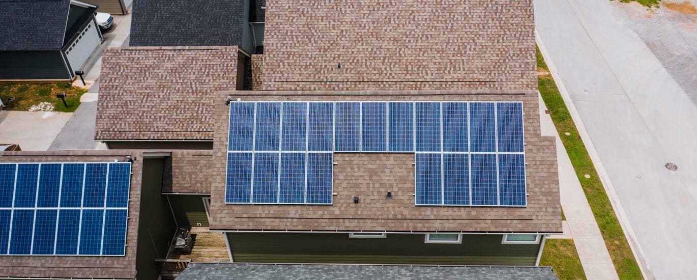 Drone shot of solar panels on residential roofs promoting eco-friendly energy solutions.