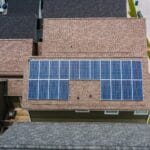 Drone shot of solar panels on residential roofs promoting eco-friendly energy solutions.