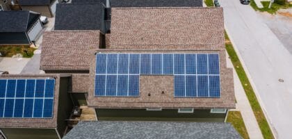 Drone shot of solar panels on residential roofs promoting eco-friendly energy solutions.