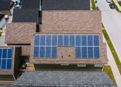 Drone shot of solar panels on residential roofs promoting eco-friendly energy solutions.